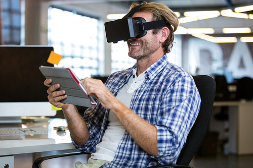 Happy creative businessman using virtual reality simulator in office