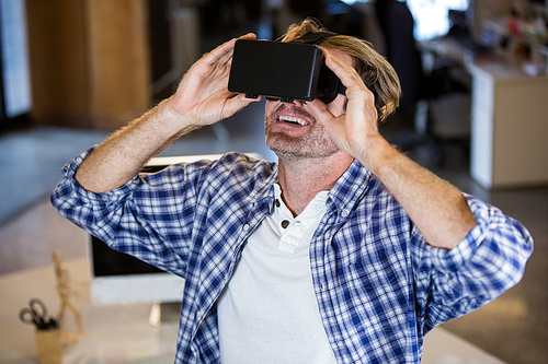 Creative smiling businessman using virtual reality simulator in office