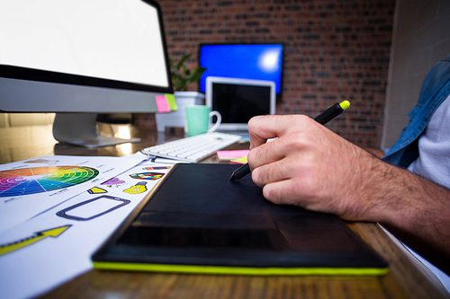 Cropped image of man using graphics tablet in creative office