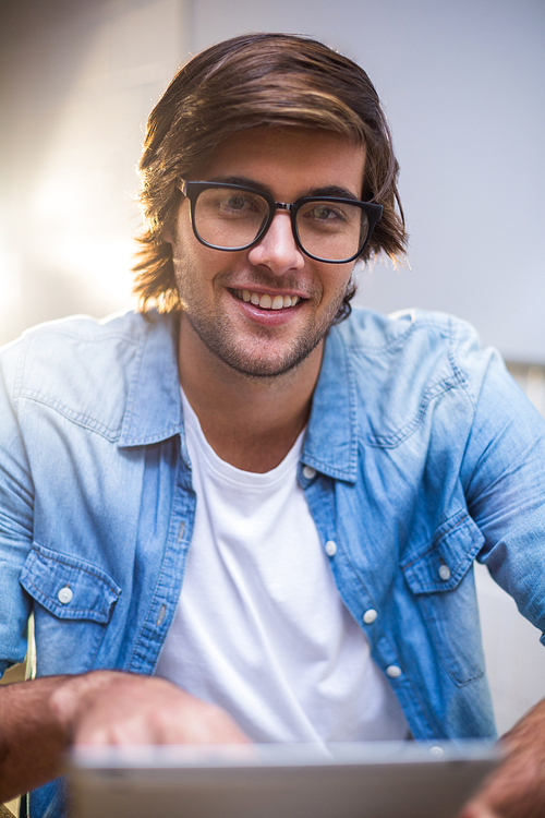 Portrait of happy young man using in creative office