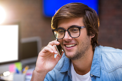 Happy young man talking on phone in creative office