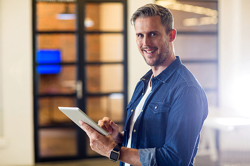 Portrait of smiling  man using digital tablet in creative office
