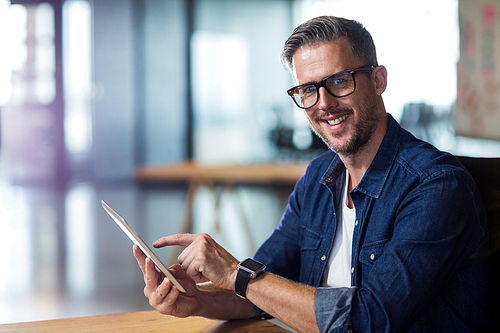 Portrait of smiling man using digital tablet in creative office