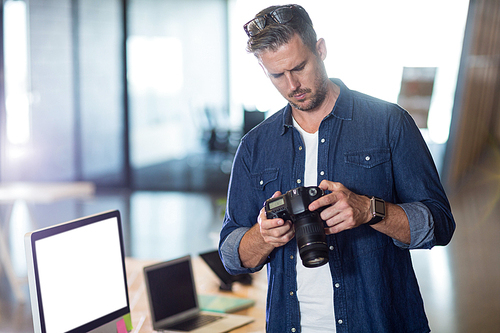 Focused man holding camera in creative office