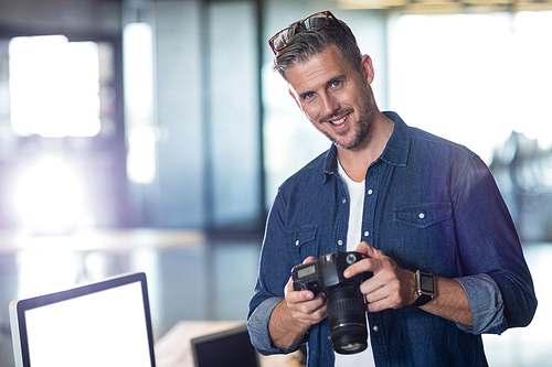 Portrait of man holding camera in creative office