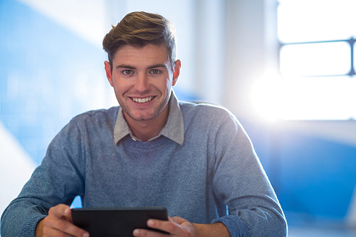 Portrait of young businessman using digital tablet in creative office