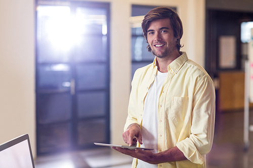 Portrait of young businessman holding digital tablet in creative office