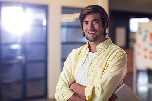Portrait of young businessman with arms crossed in creative office