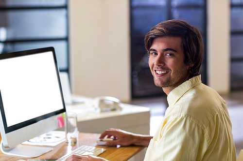 Portrait of young businessman working on computer in creative office