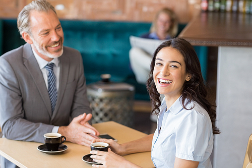 Business colleagues interacting with each other while having tea in restaurant