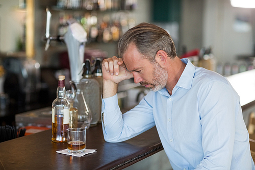 Tired man leaning his elbow on the bar counter in restaurant