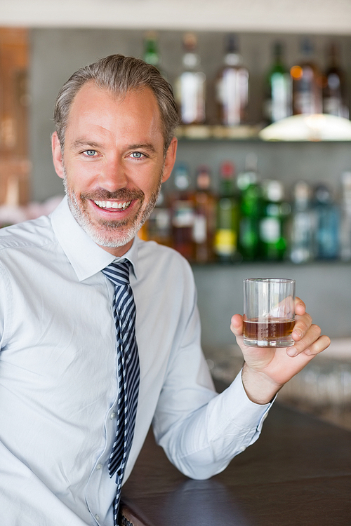 Happy man holding a glass of whiskey in restaurant