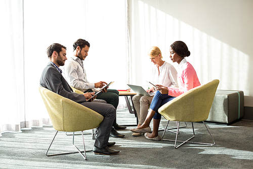 Business people using mobile phone, digital tablet and laptop in the office