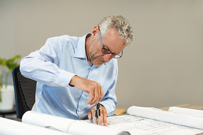 Architect working on blueprint at desk in office