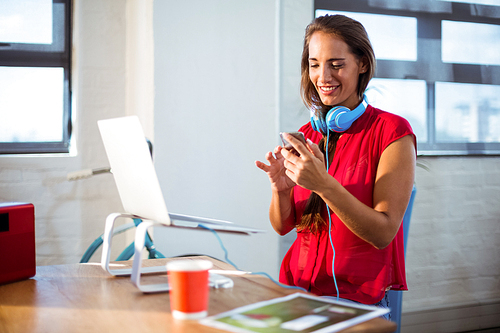 Business executive text messaging on mobile phone in office