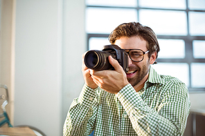 Graphic designer clicking photo from digital camera in office