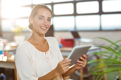 Portrait of smiling business executive holding digital tablet in office