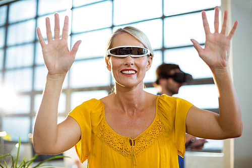 Female business executive using virtual reality video glasses in office