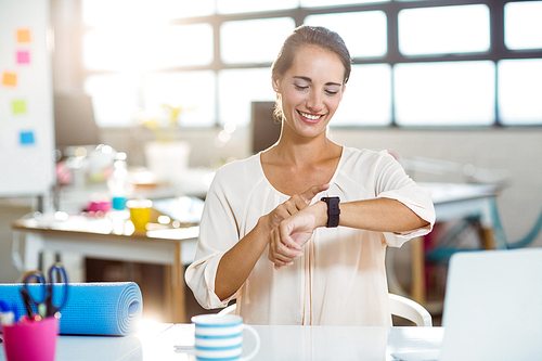 Female business executive adjusting time on her smartwatch in office