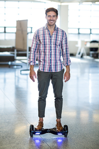 Portrait of graphic designer standing on hoverboard in office