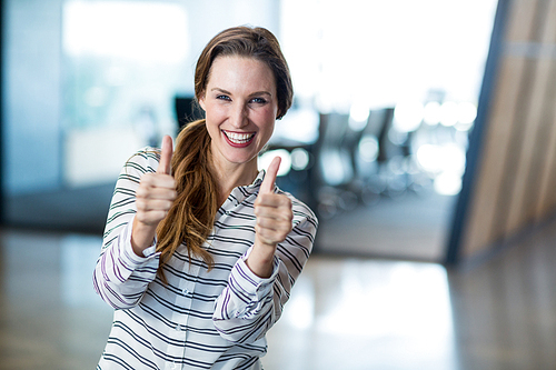 Portrait of woman showing thumbs up in office