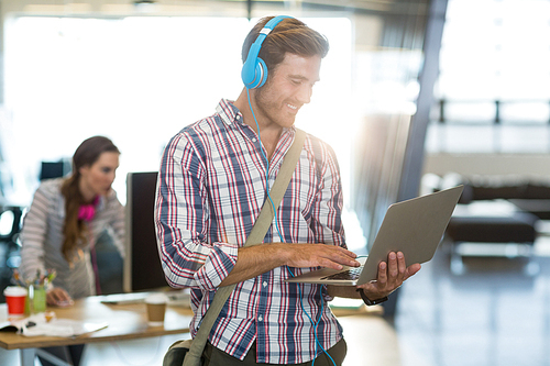 Smiling man with headphone using laptop in office