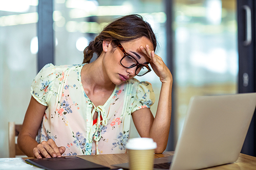 Frustrated female graphic designer looking at laptop in office