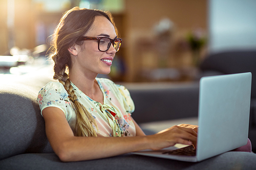 Smiling woman sitting on chair and using laptop in office