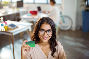 Portrait of businesswoman holding a credit card in office