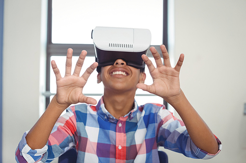 Schoolboy using virtual reality headset in classroom at school
