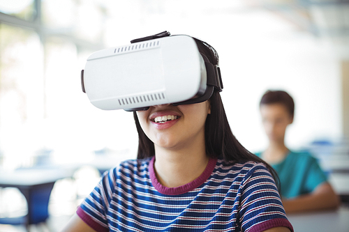 Schoolgirl using virtual reality headset in classroom at school