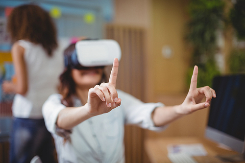 Female business executive using virtual reality headset in office