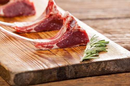 Rib chops and rosemary herb on wooden tray against wooden background
