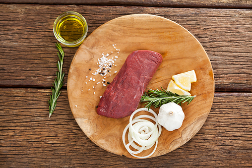 Beef steak and ingredients on wooden board against wooden background