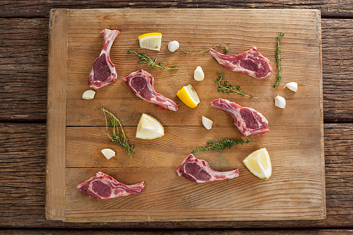 Ribs chops, lemon and garlic on wooden board against wooden background