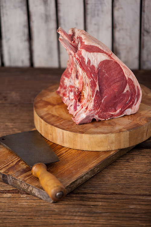 Rib rack and knife on wooden board against wooden background