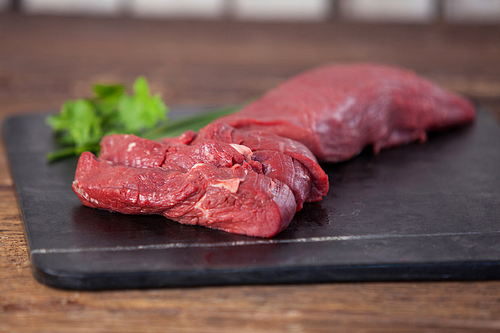 Beef steak on black slate plate against wooden background