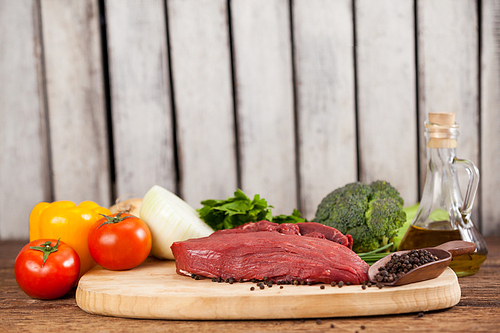 Beef steak on wooden board with ingredients against wooden background
