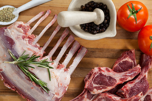 Rib rack, rib chops and ingredients on wooden board against wooden background