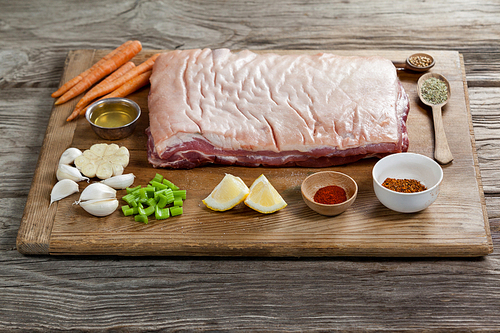 Beef brisket and ingredients on wooden board against wooden background