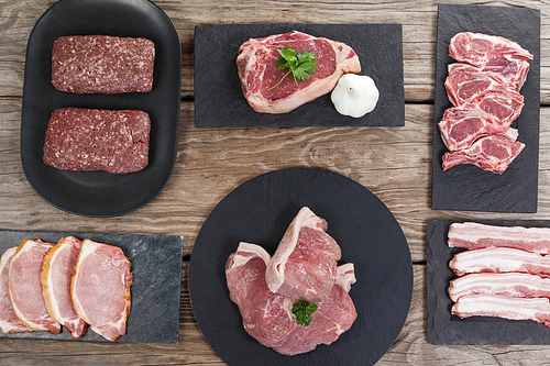 Varieties of meat on black tray against wooden background
