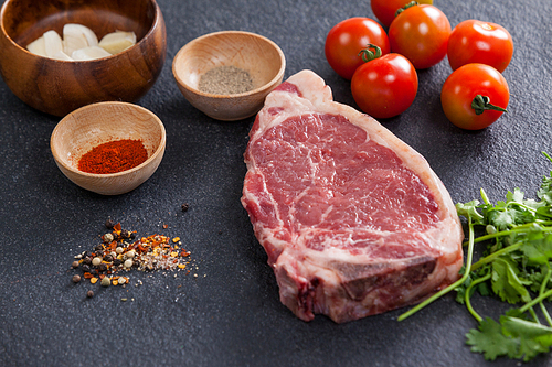 Sirloin chop and ingredients against black background