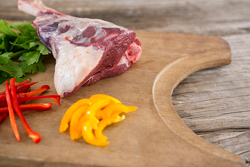 Raw rip chop, bell pepper and corainder leaves on wooden tray against wooden background
