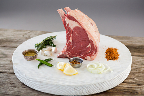 Rib chop and ingredients on white board against wooden background
