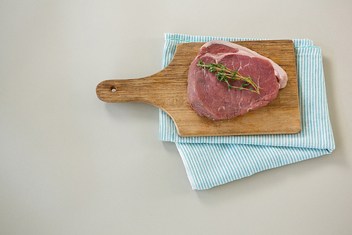 Sirloin chop on wooden tray with cooking cloth against white background