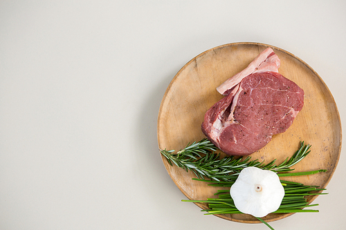 Sirloin chop, rosemary herb and garlic on wooden tray against white background