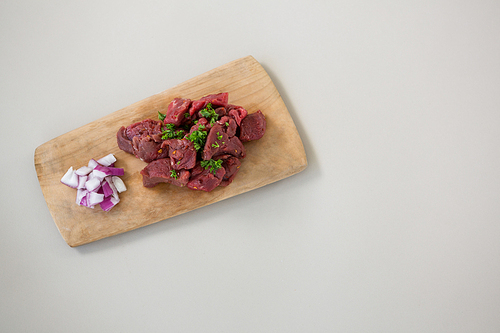 Minced beef and chopped onions on wooden tray against white background