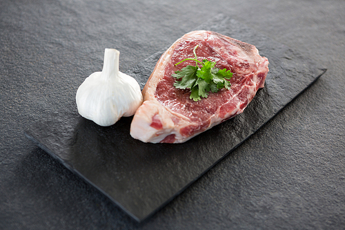 Sirloin chop and garlic on slate plate against black background