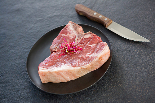 Sirloin chops garnished with shredded cabbage and knife against black background