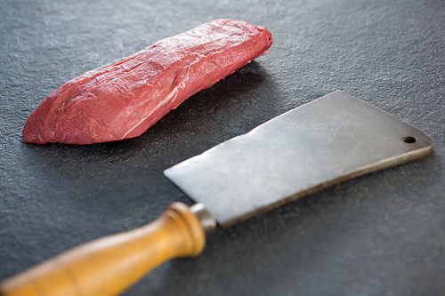 Beef steak and cleaver against black background